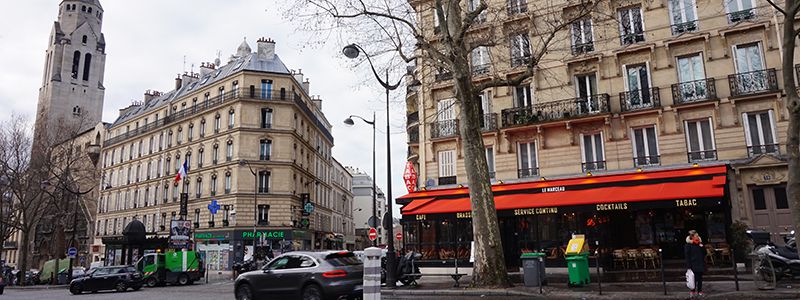 Kvarter i centrala Paris med cafeer, kyrktorn och trafik.